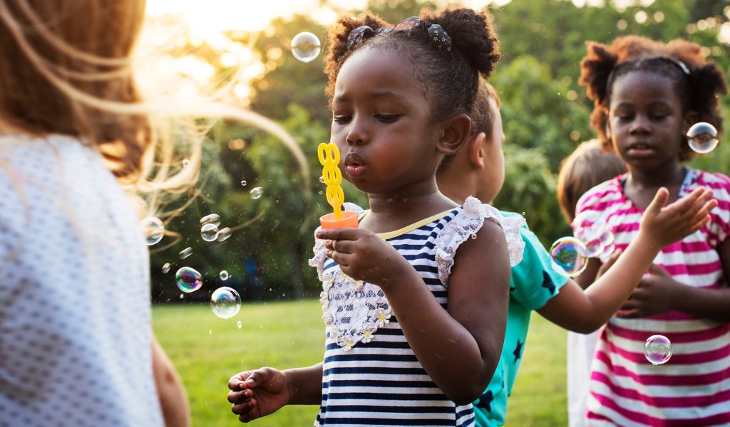 Group of kindergarten kids friends playing blowing bubbles fun