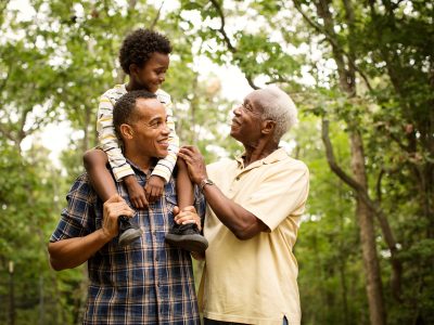 Boy (6-7) face to face with grandfather in forest